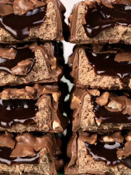 Stacked Barebells Hazelnut Spread protein bars showing cross-sections with tan cake layers and dark chocolate coating with hazelnut pieces