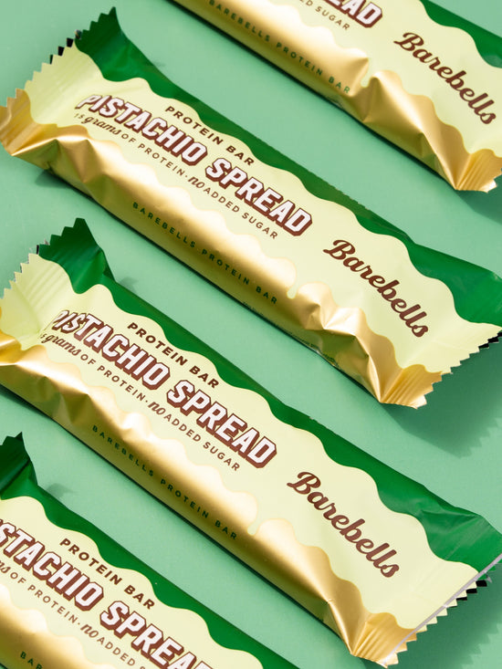Four Barebells Pistachio Spread protein bars in cream and green packaging arranged diagonally
